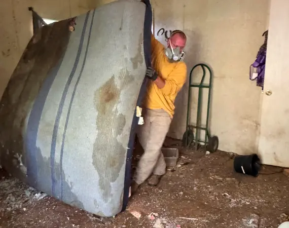 Crew member carrying out an old mattress