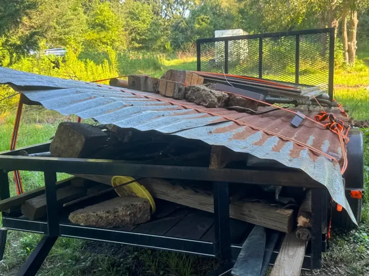 Trailer stacked with old metal roofing and lumber from a teardown