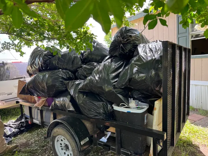 Trailer piled high with bagged trash from a house cleanout