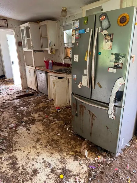 Kitchen with refrigerator and debris before a cleanout