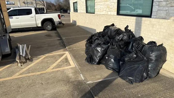 Bagged trash staged in a commercial parking lot for pickup